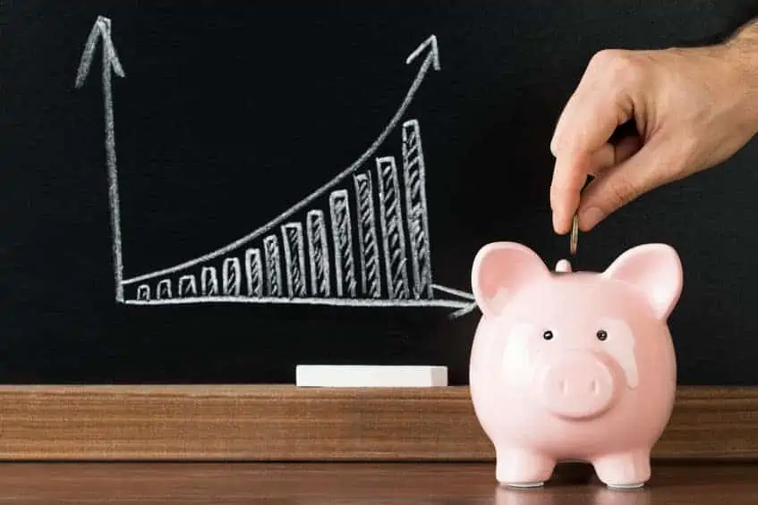 A person inserting a coin in a piggy bank with a savings growth chart.