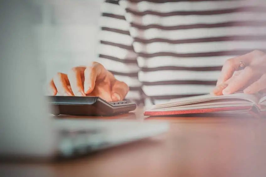 A woman with her financial notebook and calculator planning how much to save