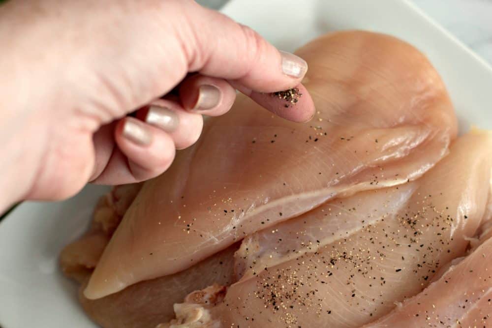 Seasoning chicken breasts.