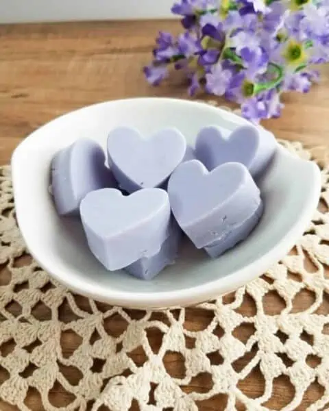 Homemade heart shapped lavender soap bars in a white bowl.