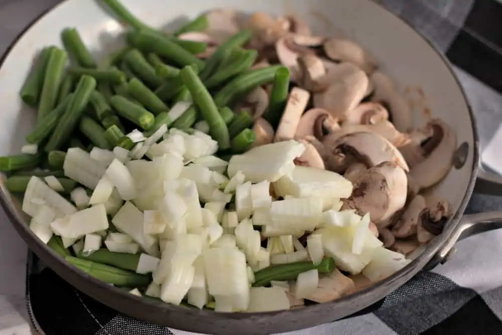 Add onions, green beans, and mushrooms to casserole dish.