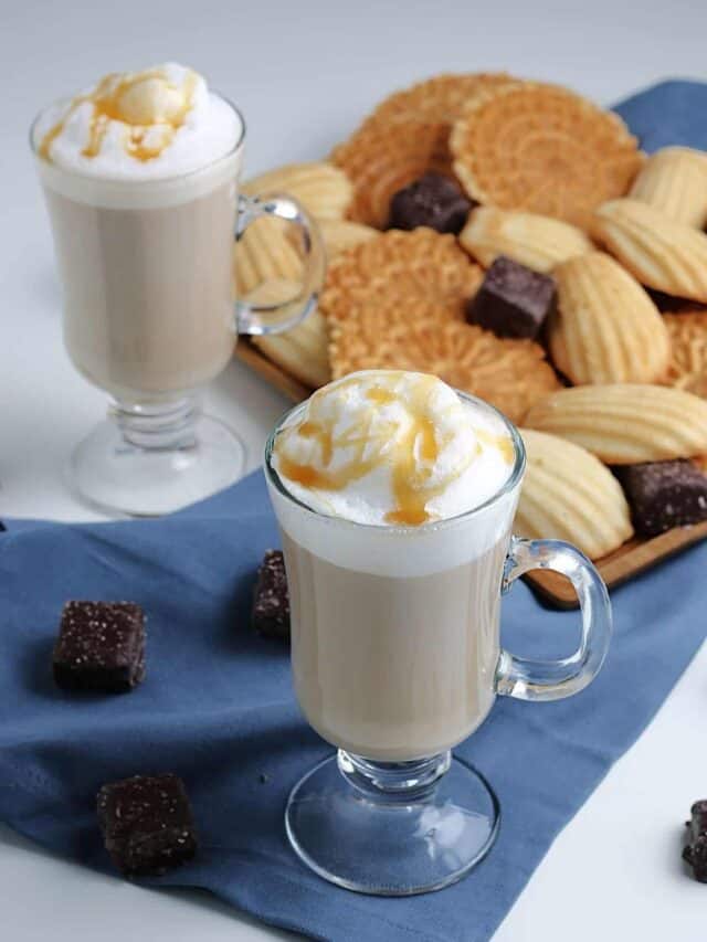 Homemade caramel vanilla latte in front of a plate of cookies.