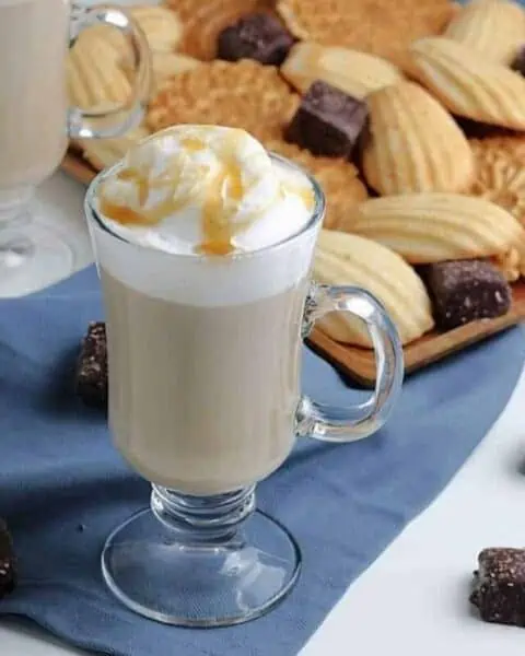 Vanilla latte drink in front of a plate of cookies.