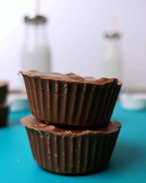 two homemade peanut butter cups stacked together with a bottle of white milk in the background