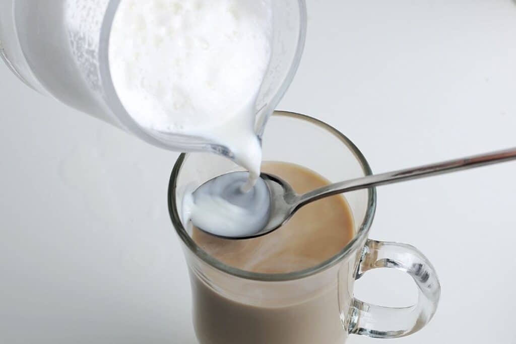 Pour the milk slowly over the spoon to hold back the foam.