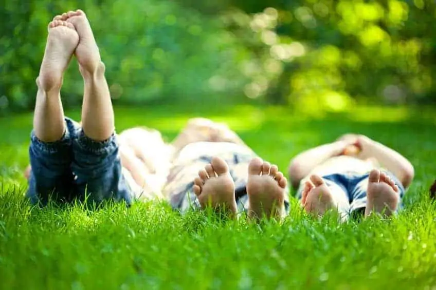 A small group of children laying on the green grass laughing and talking with each other.