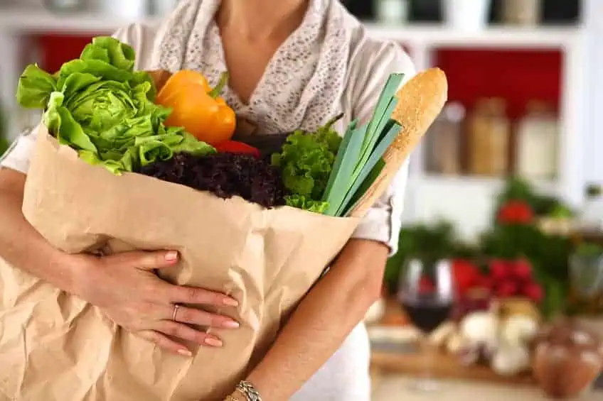 woman holding a bag of healthy groceries.