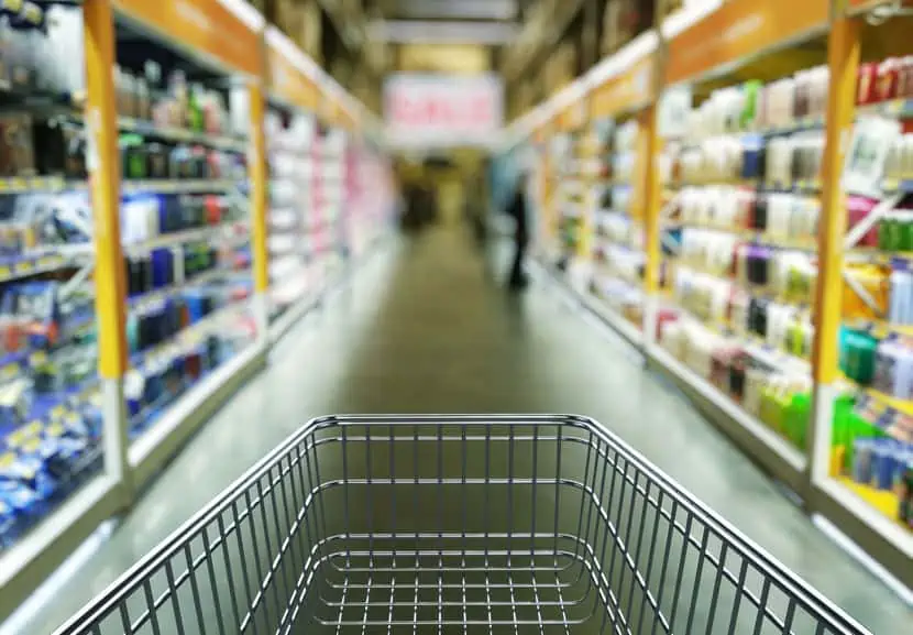 An empty grocery cart in the middle of a grocery store.