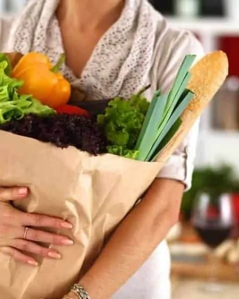 woman holding a paper bag filled with fresh produce