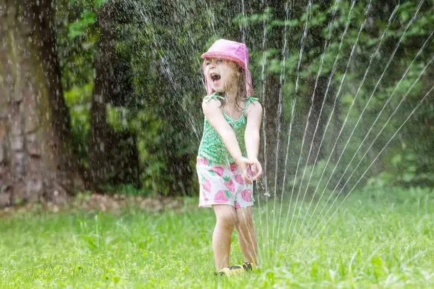 Girl playing in the sprinklers.