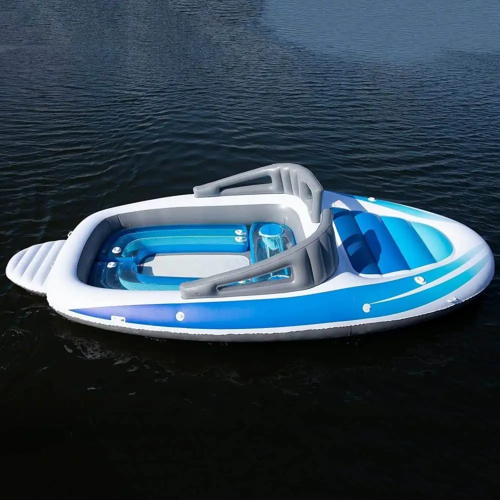 A blue and white boat sitting next to a body of water.  Life-size Inflatable Speed Boat