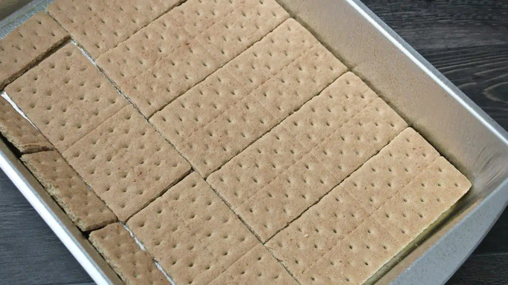 adding the graham cracker crust to the bottom of the pan 