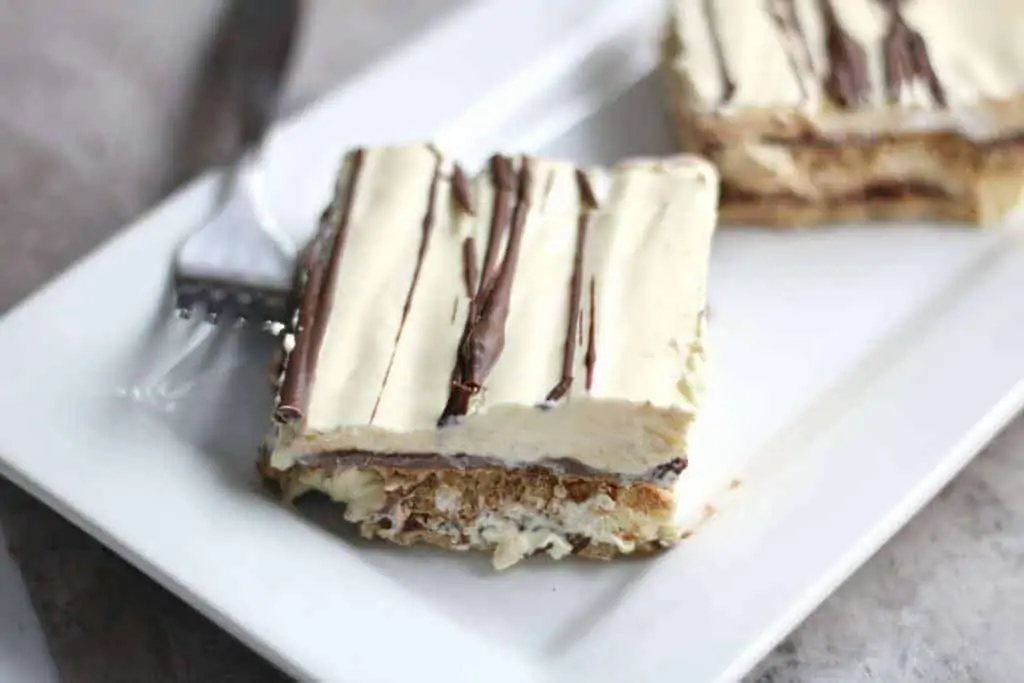 Eclair freezer cake cut into pieces on white plate with fork 