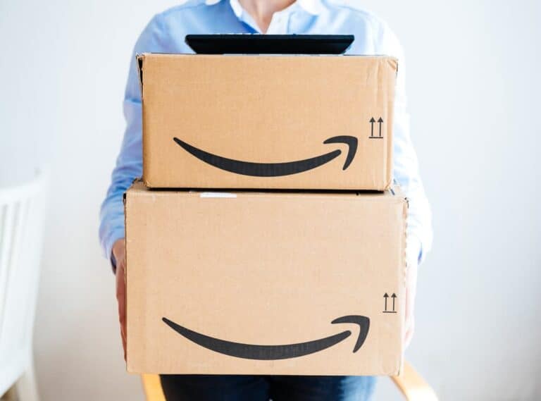A woman holding a stack of Amazon boxes.