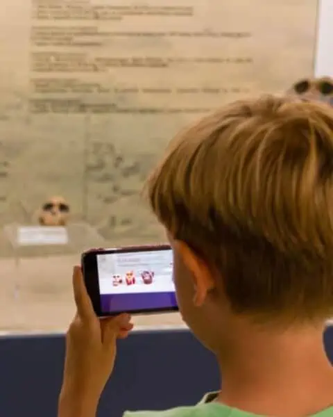 A child holding a smart phone close to his face to take a picture.