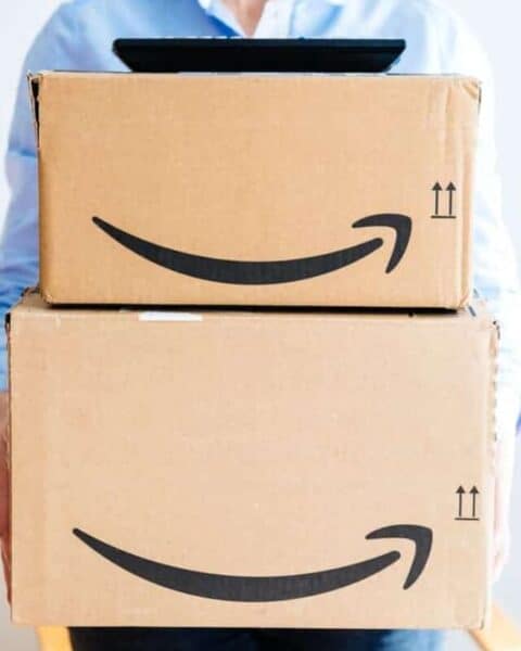 A woman holding a stack of Amazon boxes.