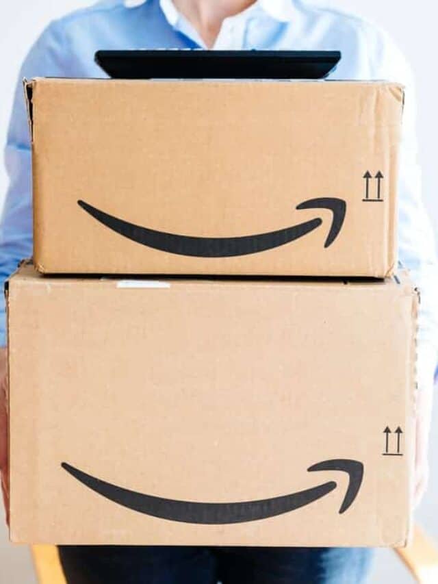 A woman holding a stack of Amazon boxes.