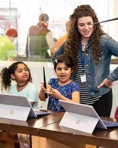 a teacher with two kids at laptops working