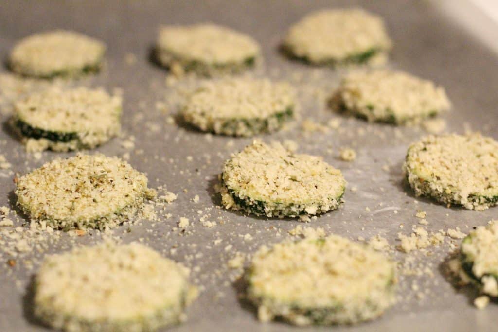 laying out chips on parchment paper to bake to make Spicy Zucchini Chips