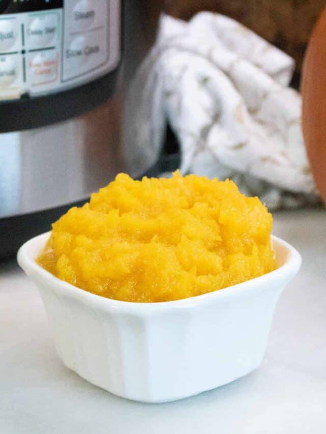 A white bowl of pumpkin puree in front of an instant pot.