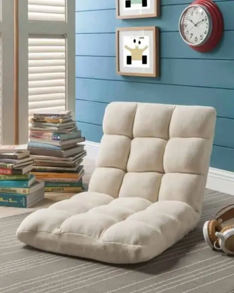 Soft foldable reclining chair in a corner with a stack of books.
