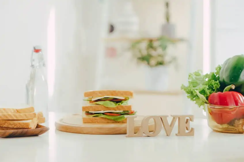 A sandwich on a plate behind a sign that reads, \"love.\"