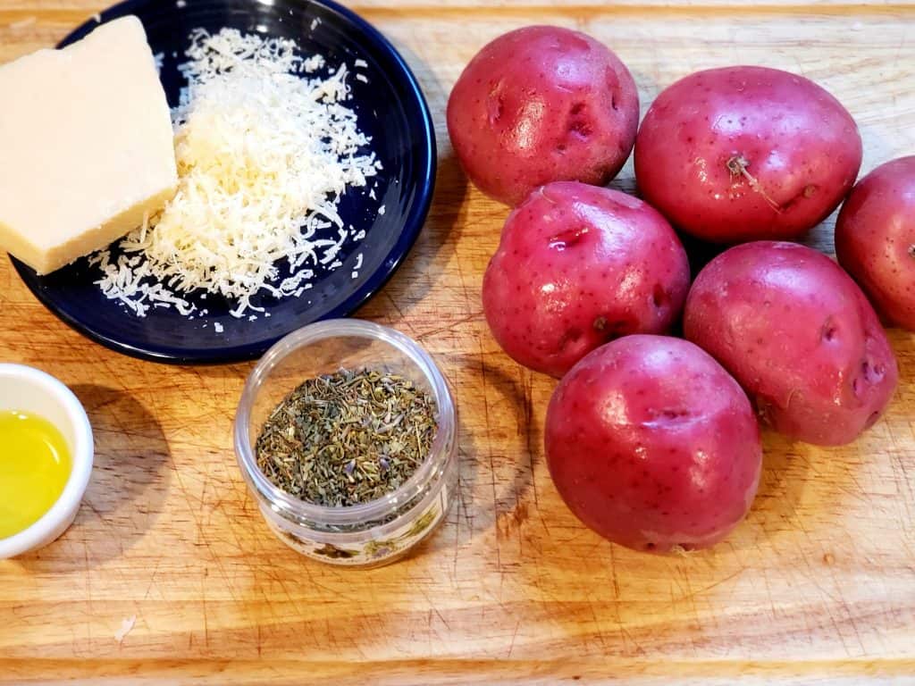 A table covered with red potatoes, cheese, and seasoning for the lavender red roasted potatoes. 