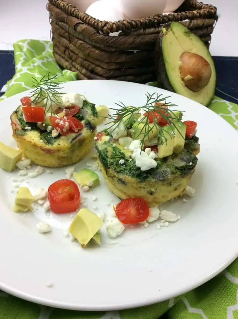 Cooked and garnished egg muffin breakfast with avocados, tomatoes, and cheese. 