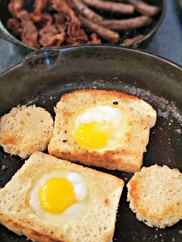 eggs cooking in a pan inside of slices of bread