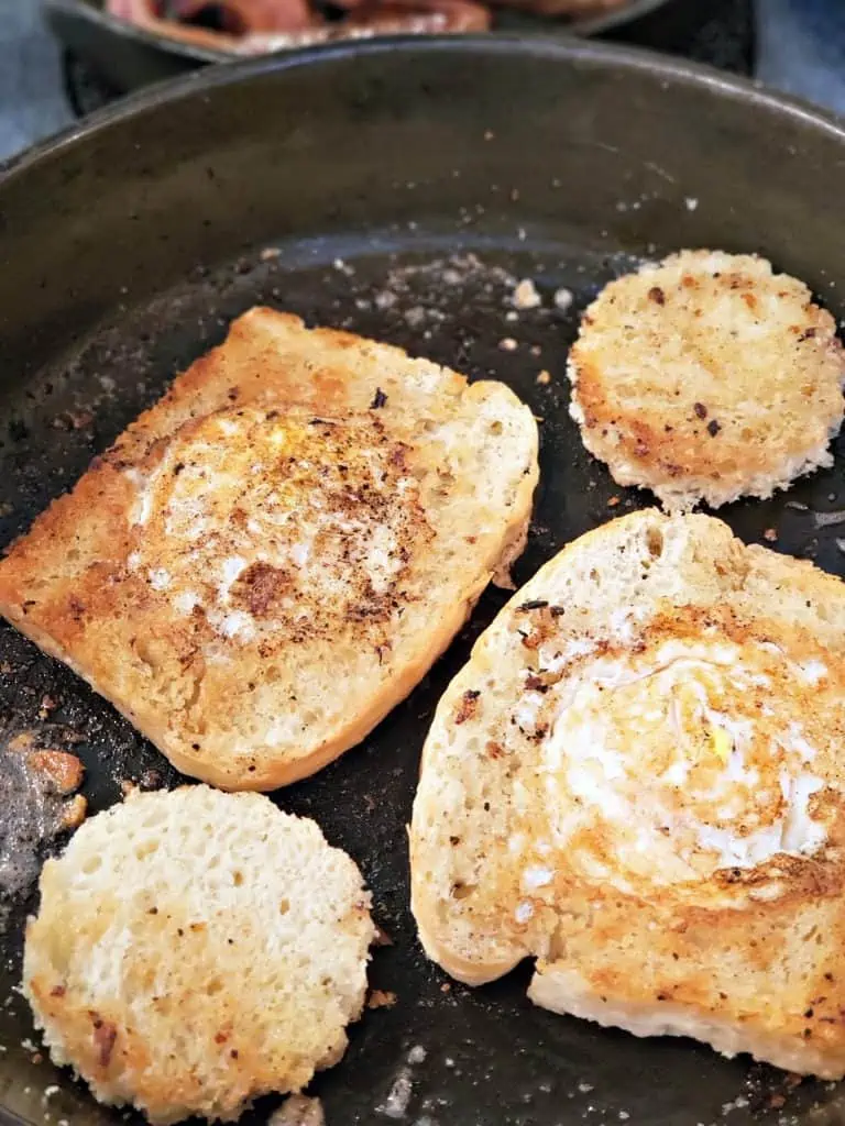 fried eggs inside slices of bread in a pan