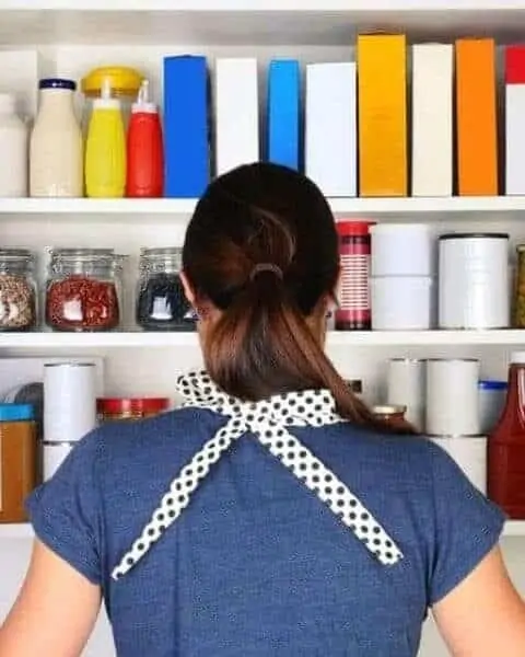woman standing in front of an open cupboard filled with food