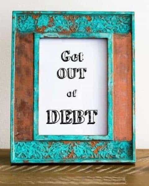a sign sitting on a wooden table that says Get Out of Debt