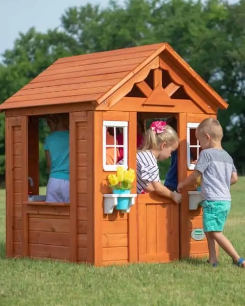 Timberlake cedar wooden playhouse with children playing together.