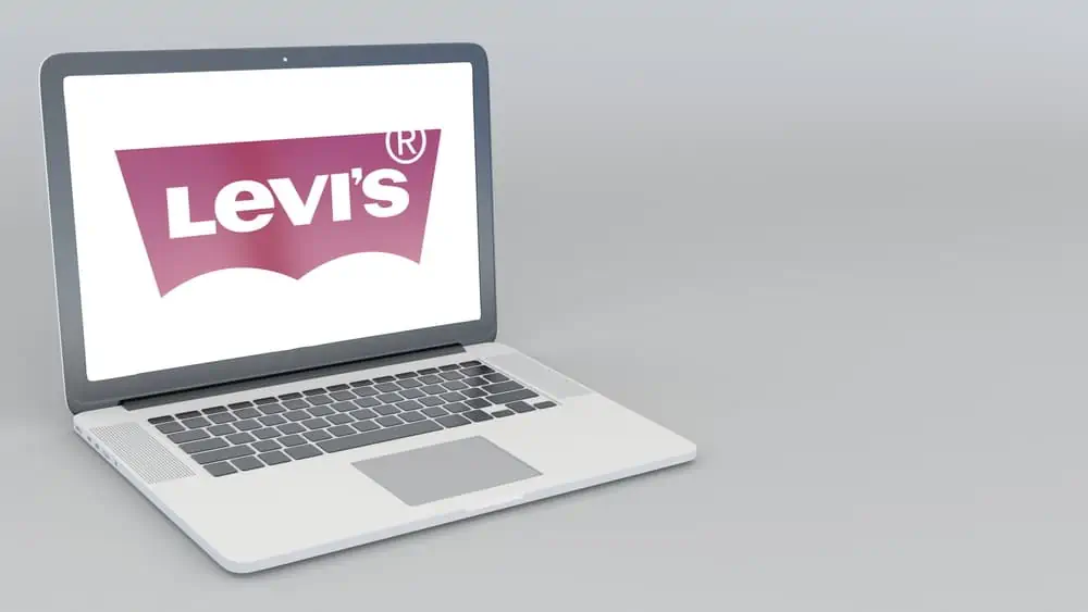An open laptop computer sitting on top of a table featuring the Levi\'s logo.