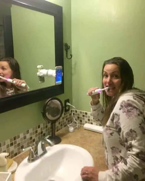 A person brushing the teeth with a rose gold Oral B 8000.