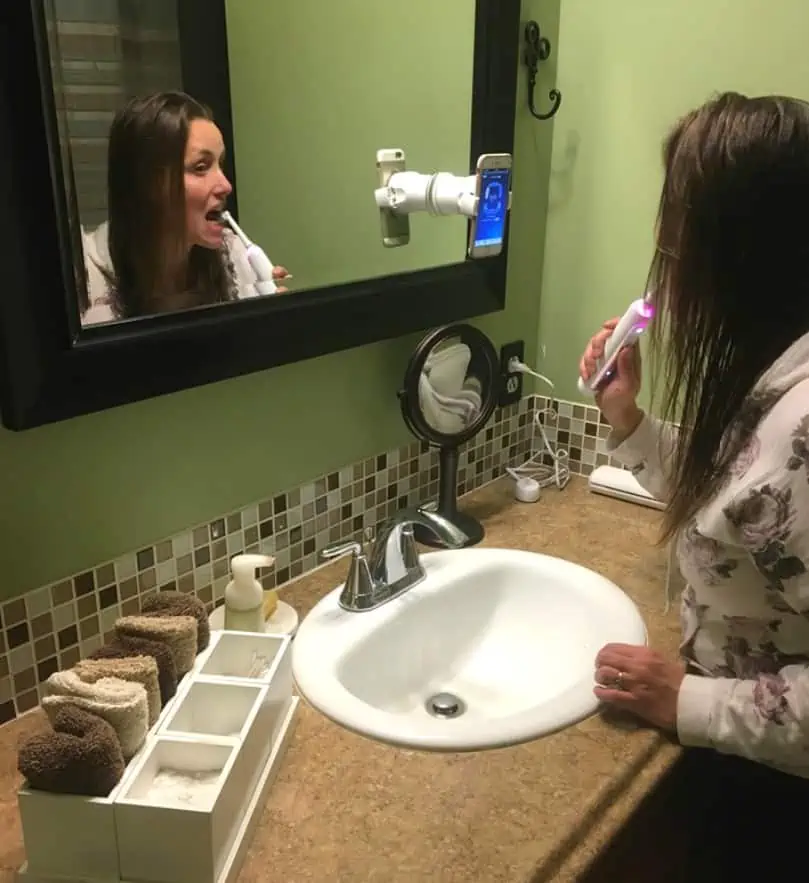 A person brushing the teeth in front of a mirror posing for the camera