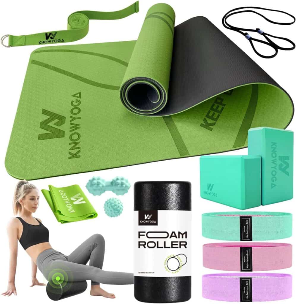 Woman using a foam roller on her legs with a green yoga mat, resistance bands, blocks, and towel nearby.