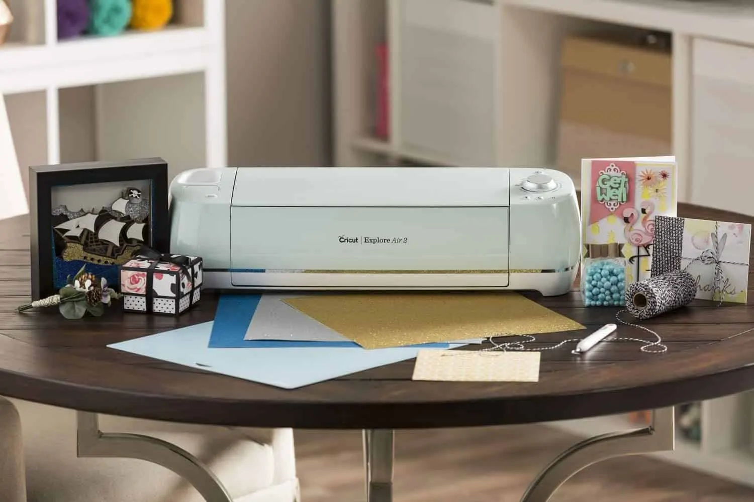 Cricut Explore Air on a crafting table surrounded by supplies.