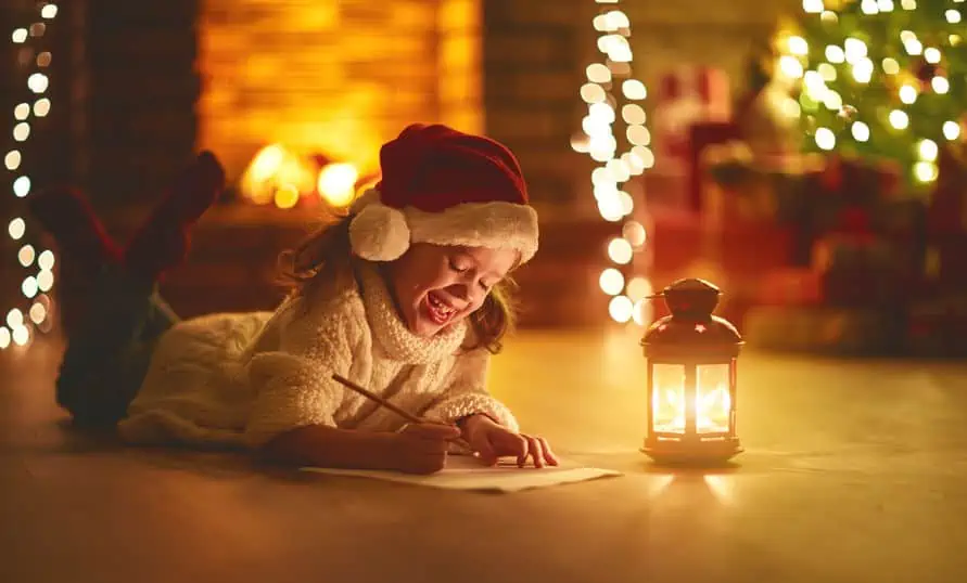 child girl writing letter santa home near the Christmas tree