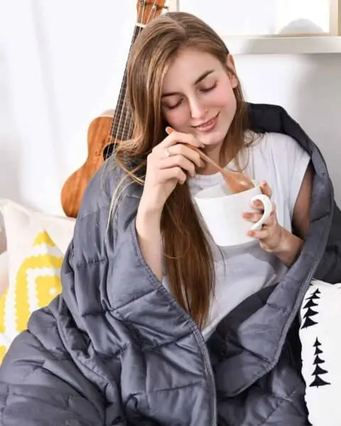 woman eating out of a bowl wrapped in a blanket