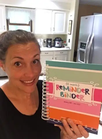 A woman smiling with her Power Planner Reminder Binder.