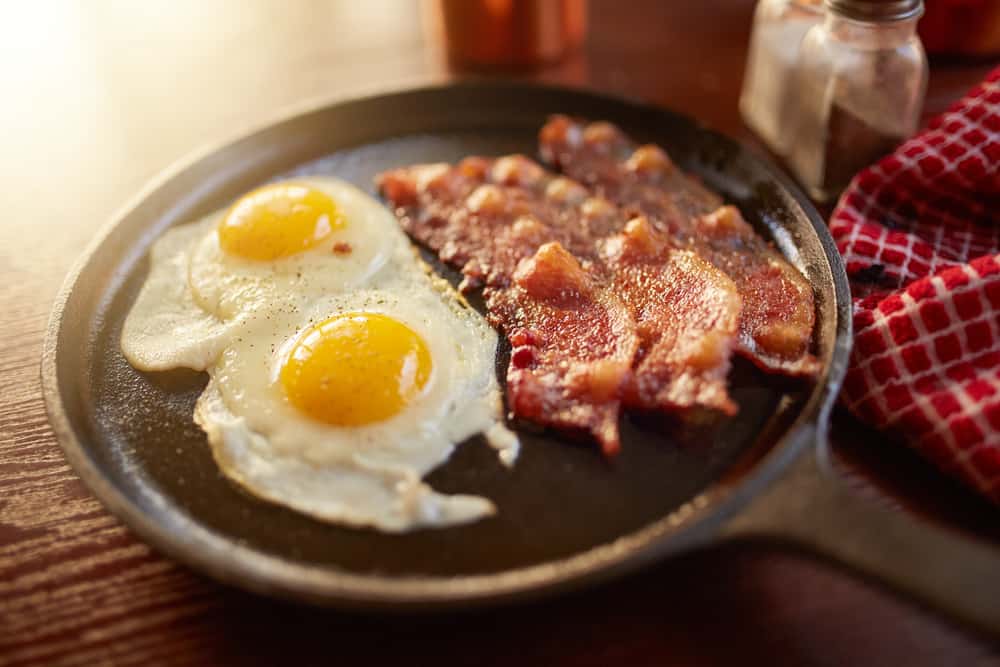 fried bacon and eggs in iron skillet