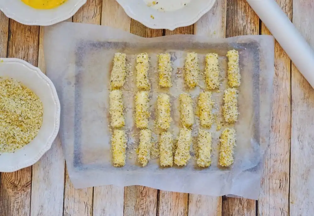 prepared mozzarella cheese sticks on a cookie sheet