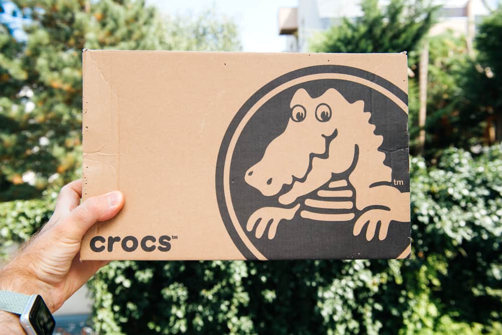 Man holding a cardboard box with new pair of new shoes by Crocs