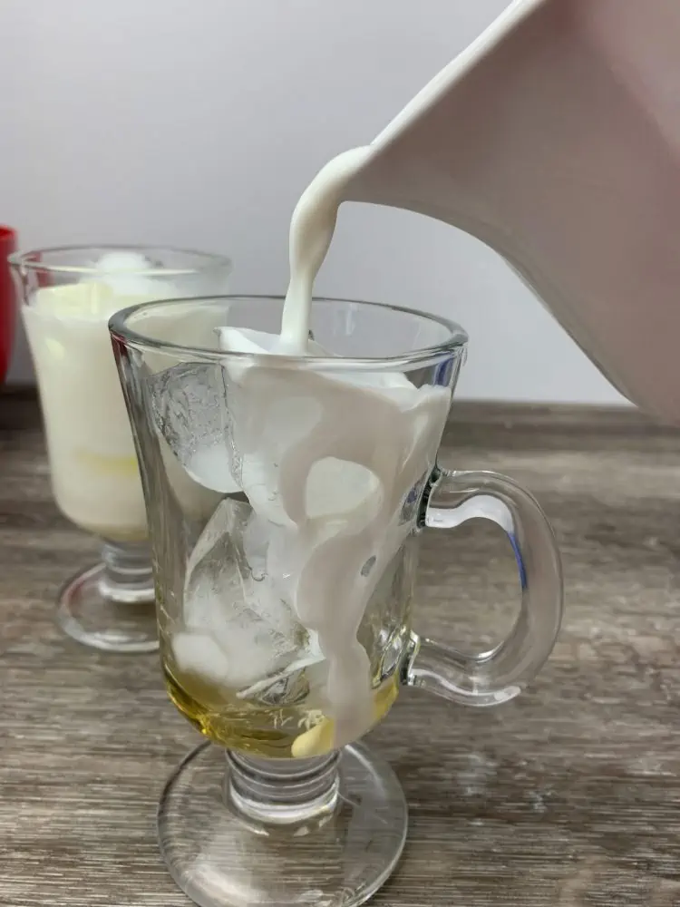 pouring milk into a glass of ice and caramel syrup