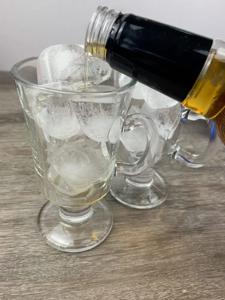 pouring salted caramel syrup into a glass of ice