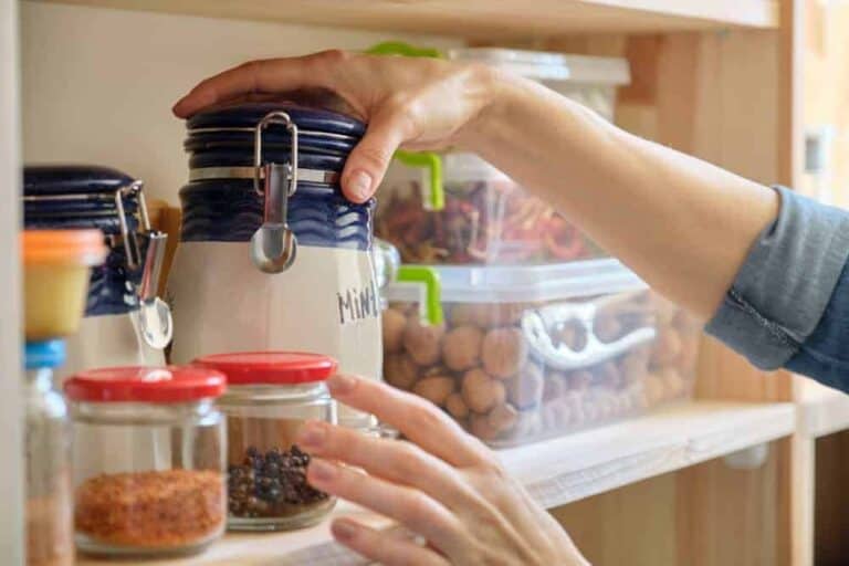 Woman in the kitchen with can of dry mint, food storage, pantry.