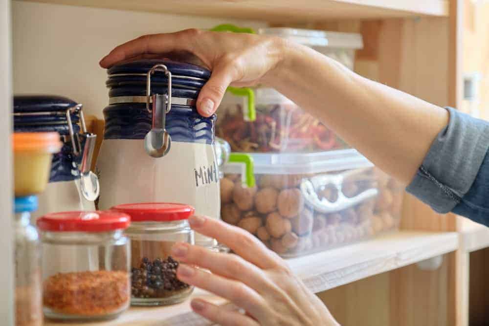 Woman in the kitchen with can of dry mint, food storage, pantry.