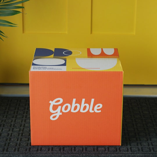 Gobble box sitting on the front porch of a house. 
