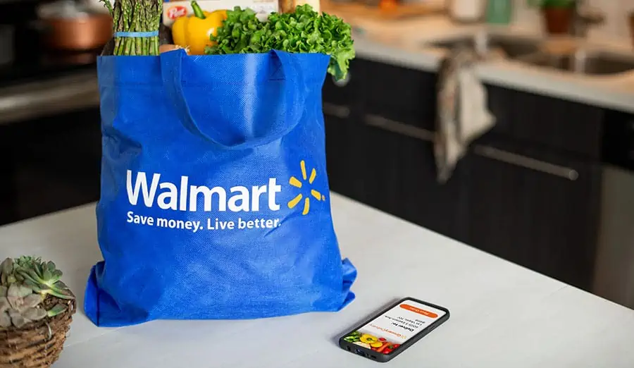 Walmart bag on a counter filled with groceries sitting next to a cell phone